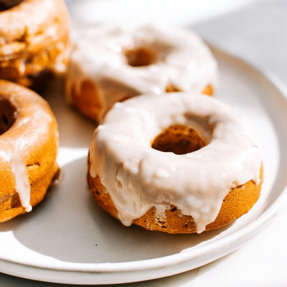 Golden maple pumpkin mochi donuts topped with sweet glaze and resting on a wire rack