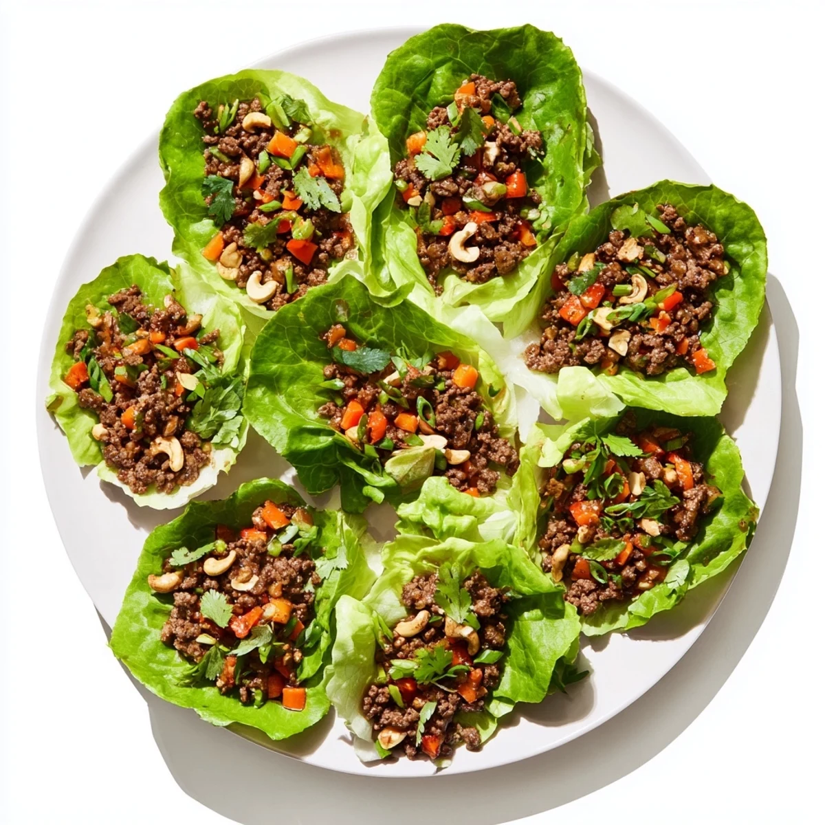 Garnished beef and cashew lettuce cups served with lime wedges and fresh cilantro sprigs