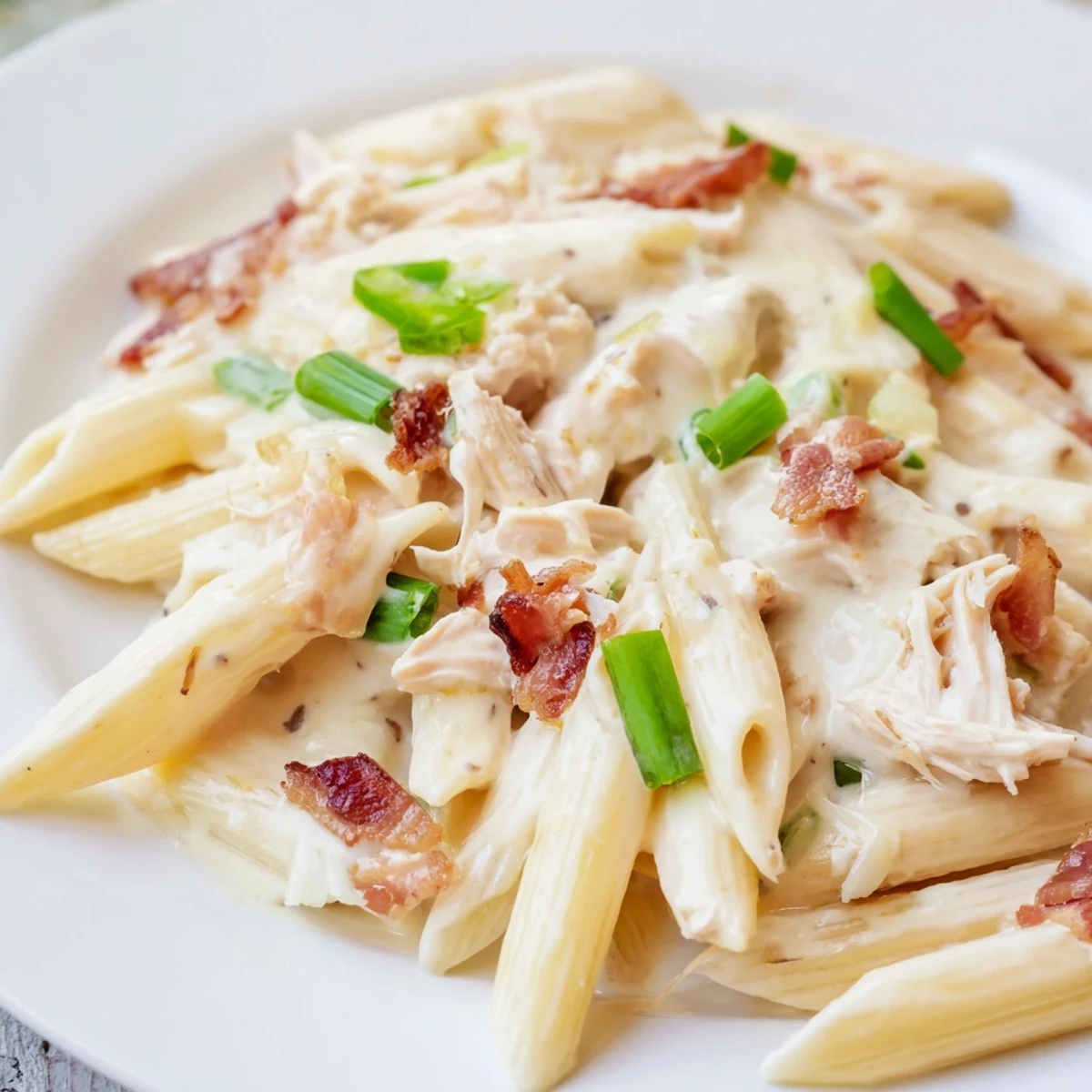 Creamy crack chicken pasta tossed with melted cheddar, crispy bacon, and green onion topping