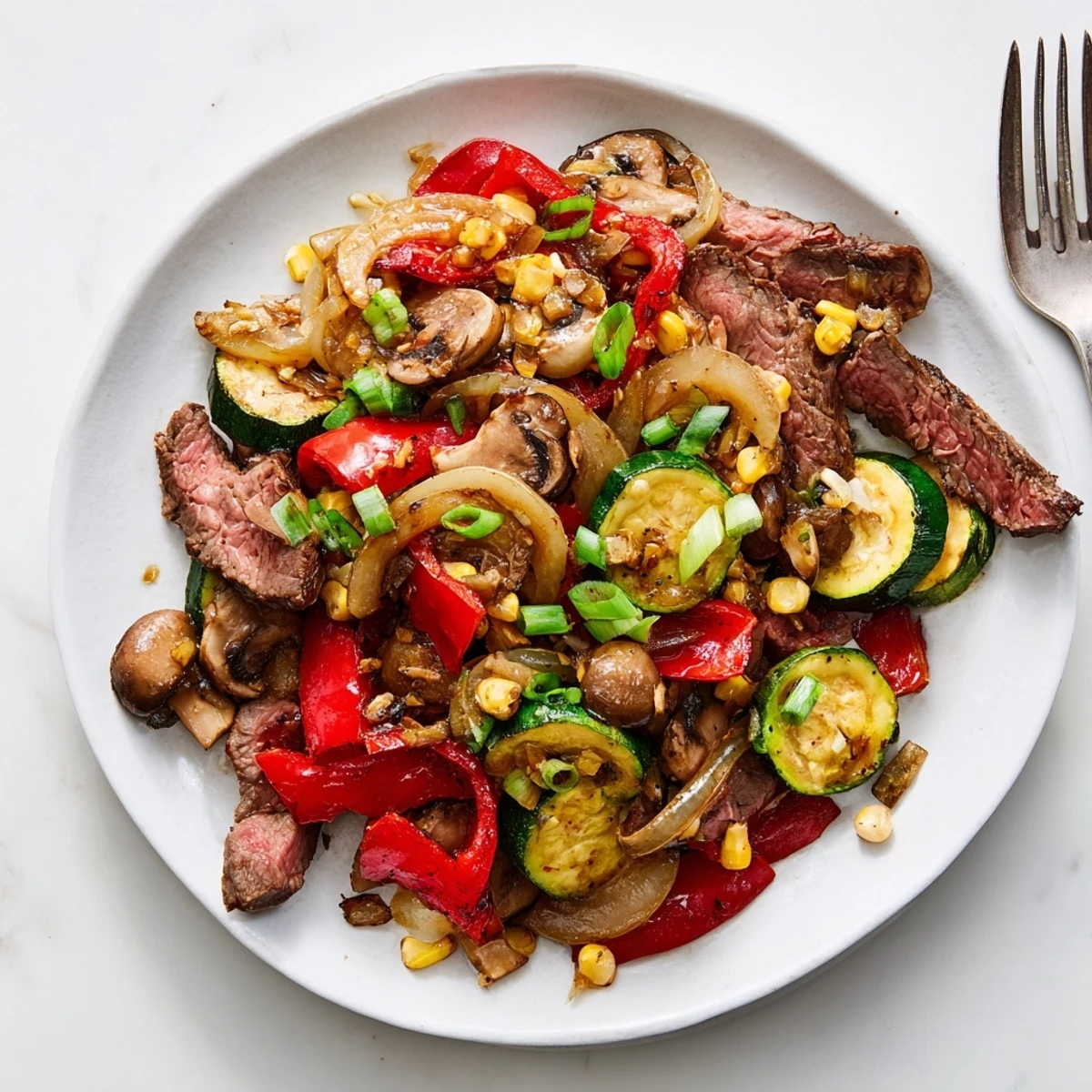Sizzling Blackstone Cowboy Stir Fry piled high with steak, corn, mushrooms, and fresh green onion garnish