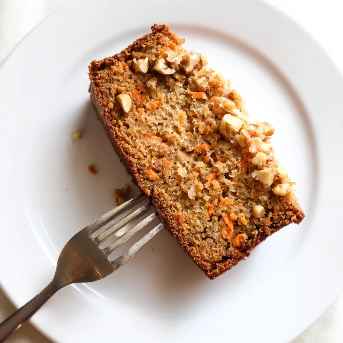 Slice of moist carrot cake banana bread revealing grated carrot texture and cinnamon spice flecks throughout