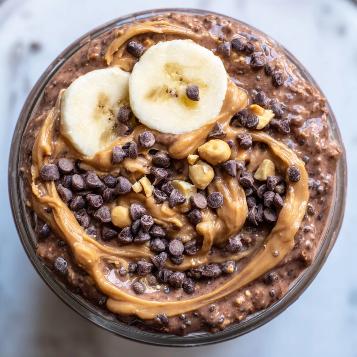 Thick chocolate peanut butter overnight oats served in a jar with fresh banana slices