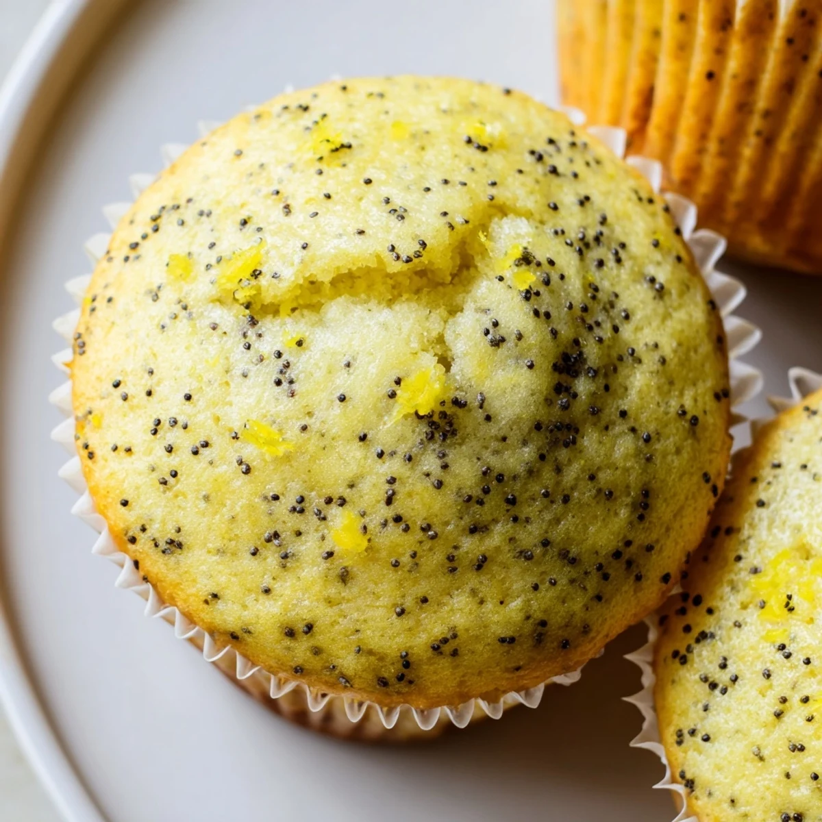 Moist lemon poppy seed muffins speckled with seeds and topped with sparkling sugar crystals.