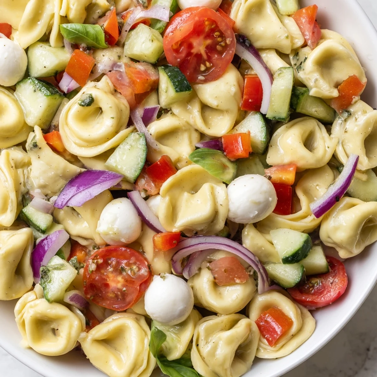 Colorful Tortellini Salad in a bowl with cherry tomatoes, cucumber, and tangy Italian dressing