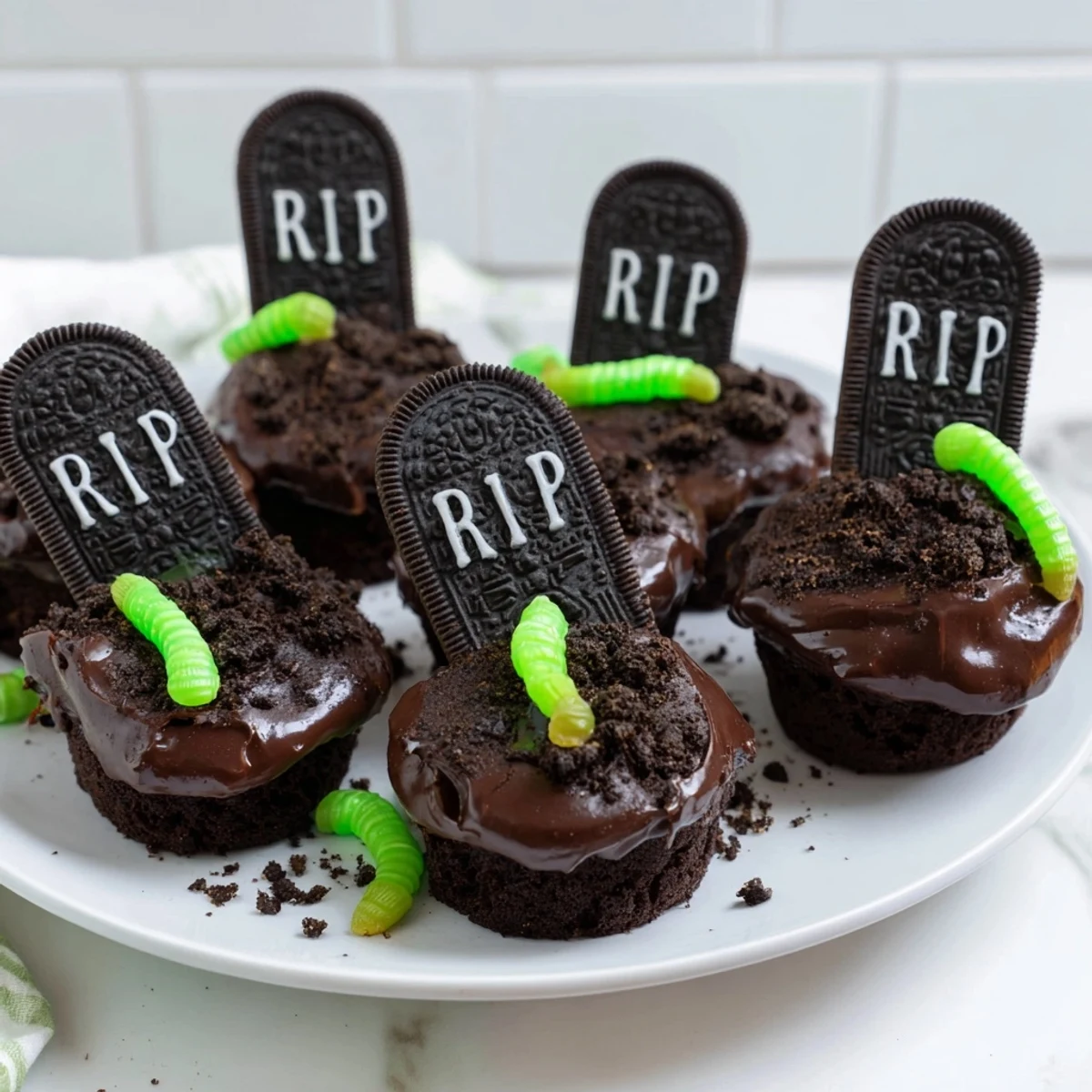 Pull Apart Graveyard Cupcakes topped with chocolate frosting, cookie dirt, and creepy tombstone decorations.
