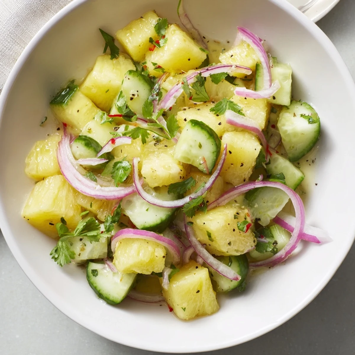 Chilled Pineapple Cucumber Salad topped with sliced red onion and chopped cilantro
