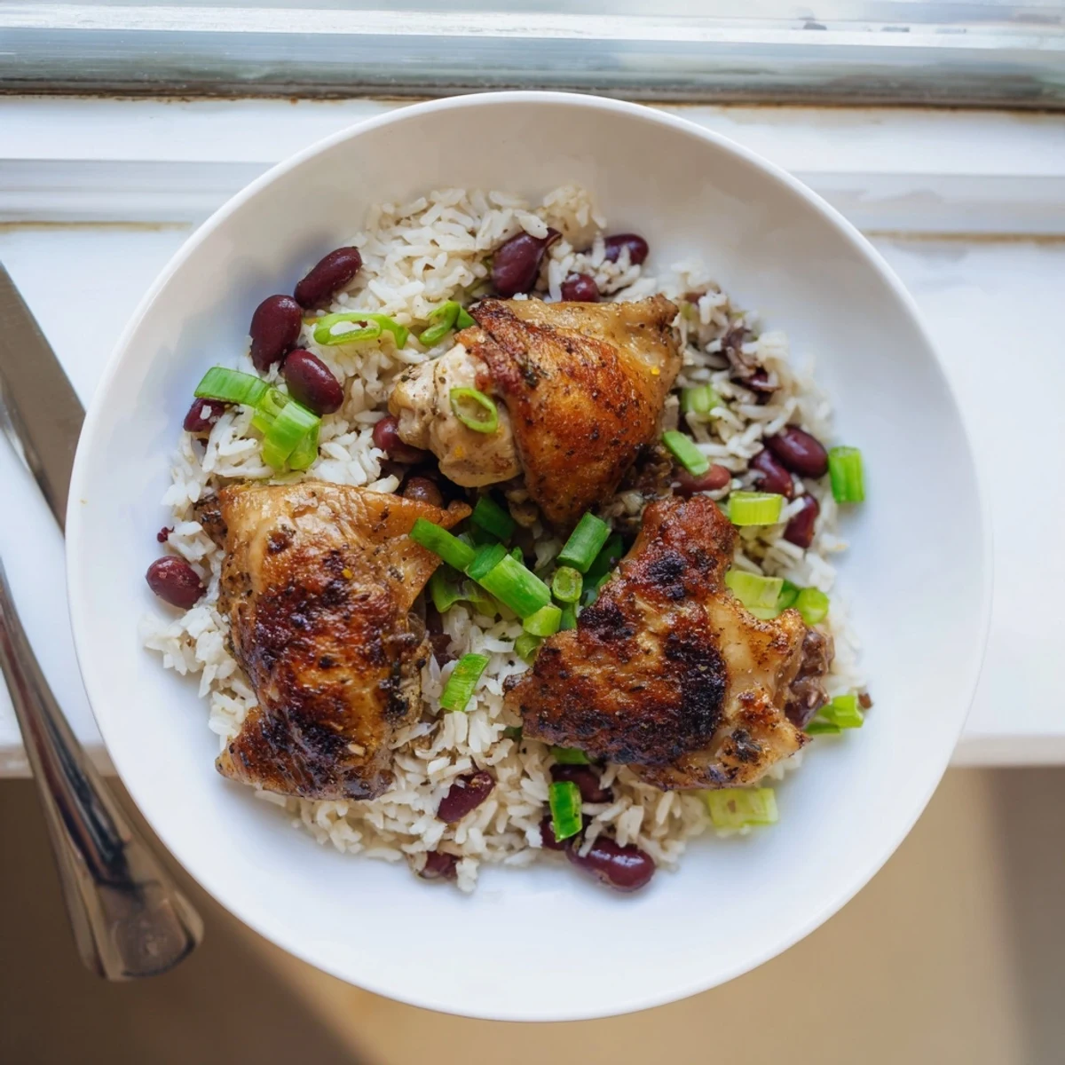 Spicy marinade glazed chicken thighs served over fragrant Caribbean rice and beans dish