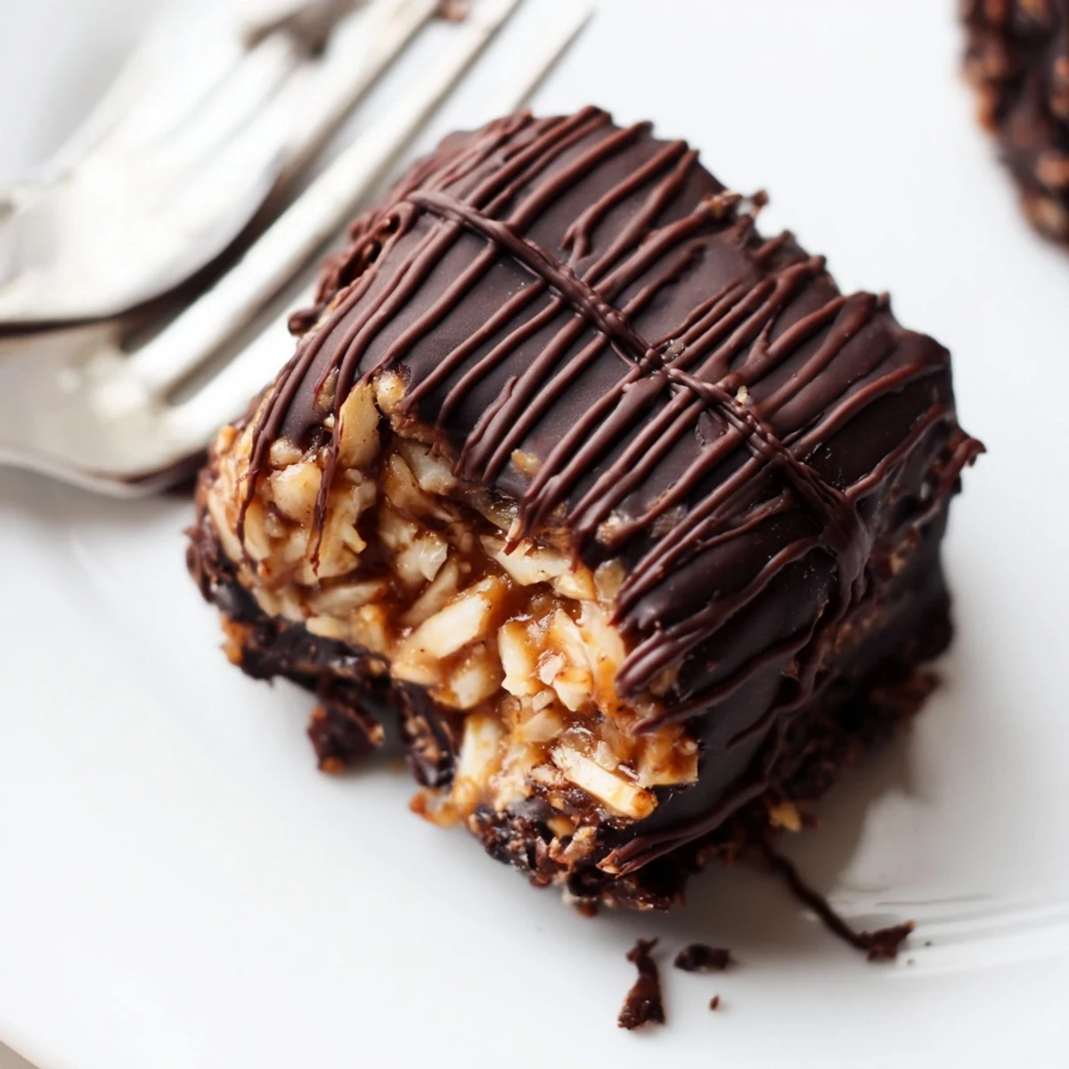 No bake Samoa bites topped with toasted coconut caramel and dark chocolate drizzle on parchment paper