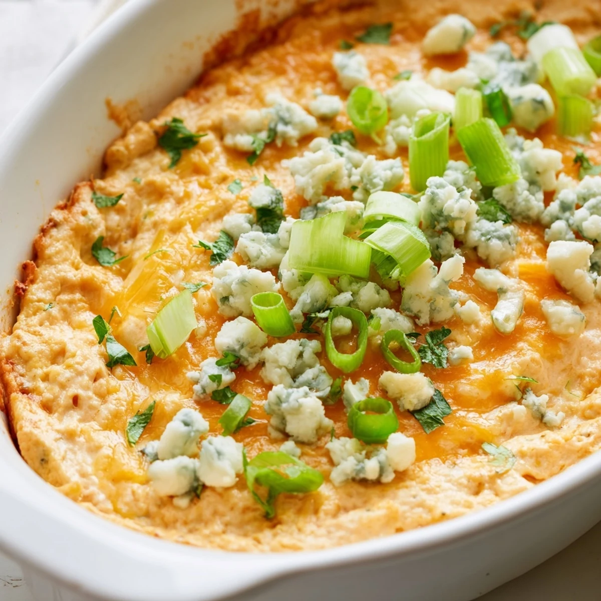 Golden cheesy white bean buffalo dip bubbling hot with melted cheddar and fresh green onions