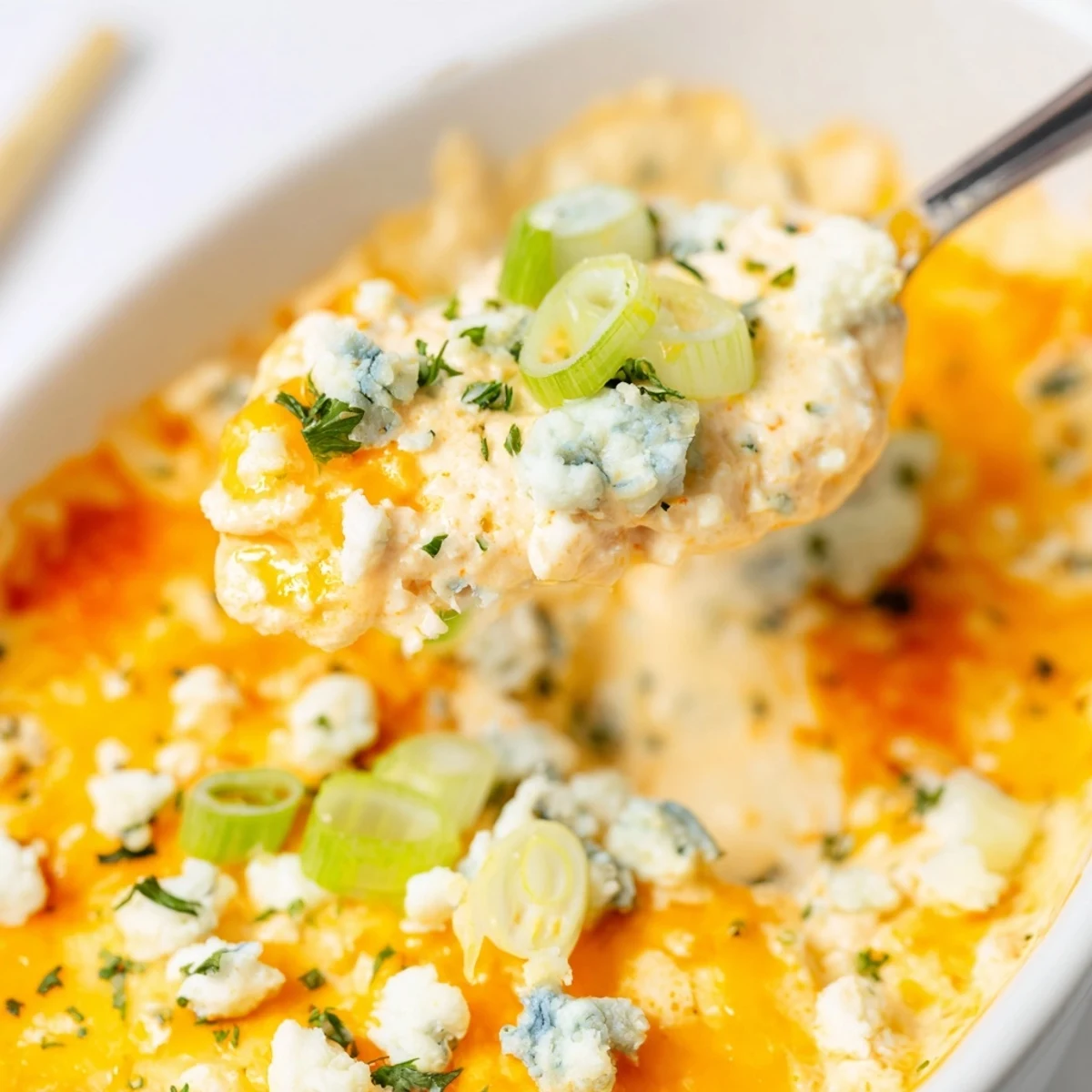 Steaming baked white bean buffalo appetizer with spicy sauce and shredded cheese ready for dipping