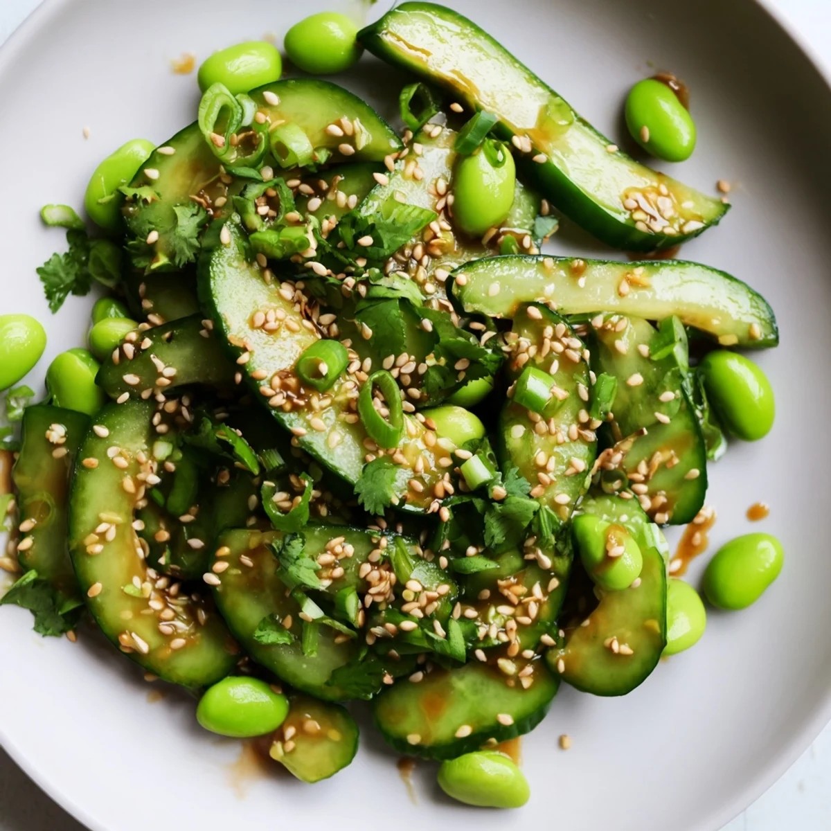 Colorful vegan salad bowl featuring sliced cucumbers, bright green edamame, and savory sesame soy dressing