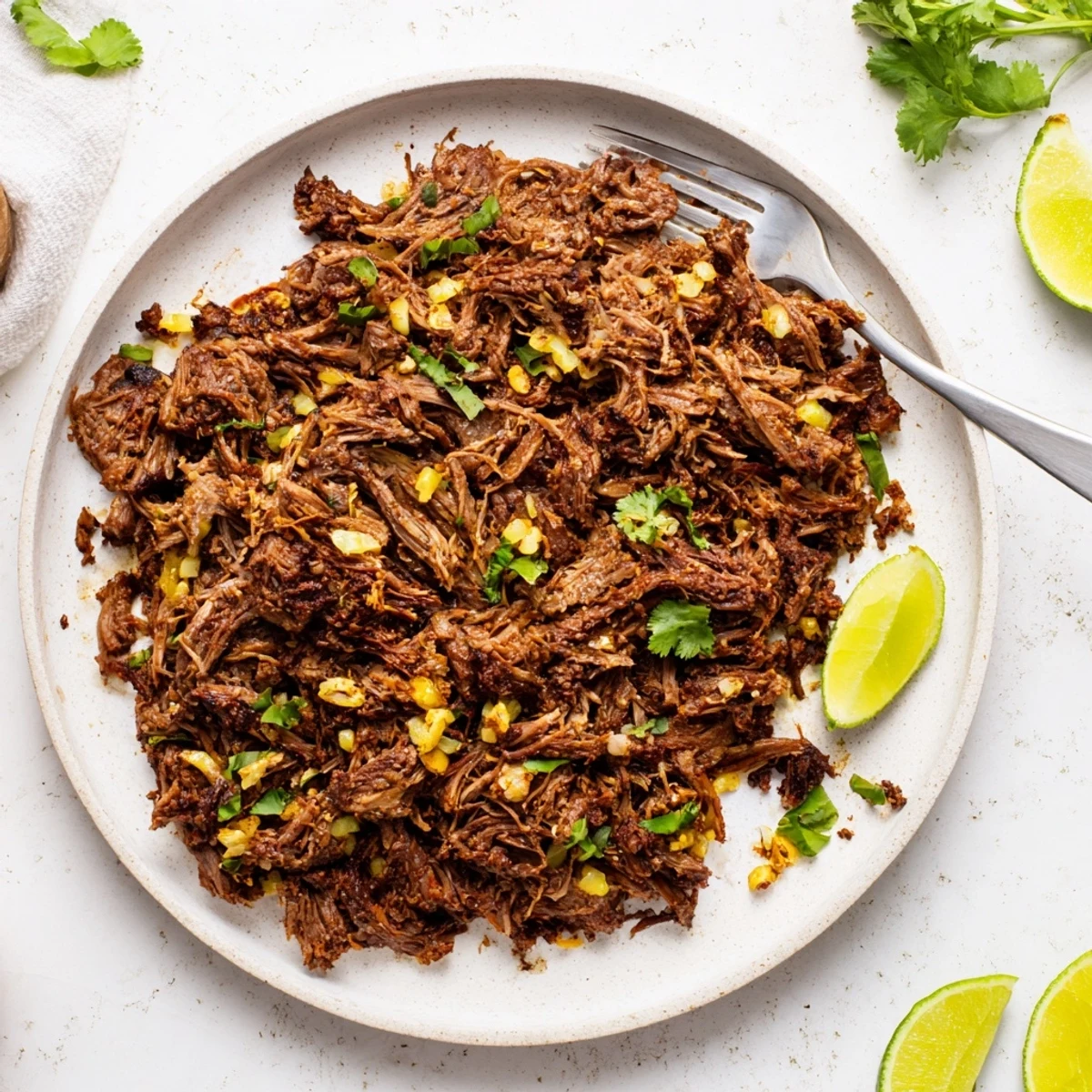 Rich and spicy slow cooker beef barbacoa serving in a bowl over fluffy white rice with toppings