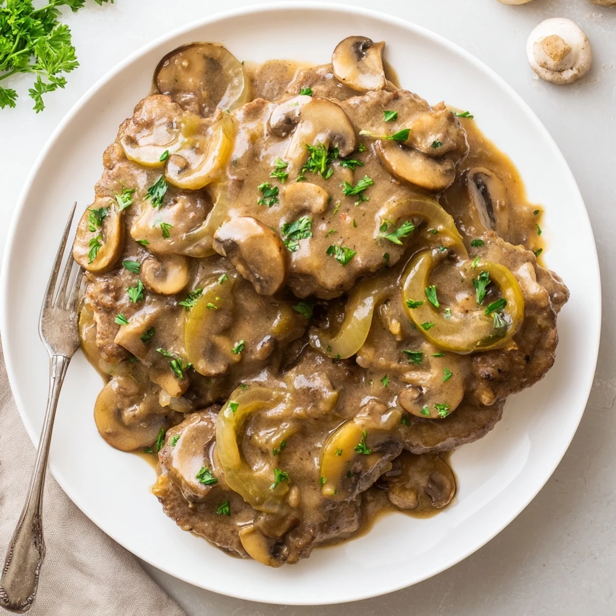 Tender smothered cube steak simmering in creamy beef gravy served over mashed potatoes