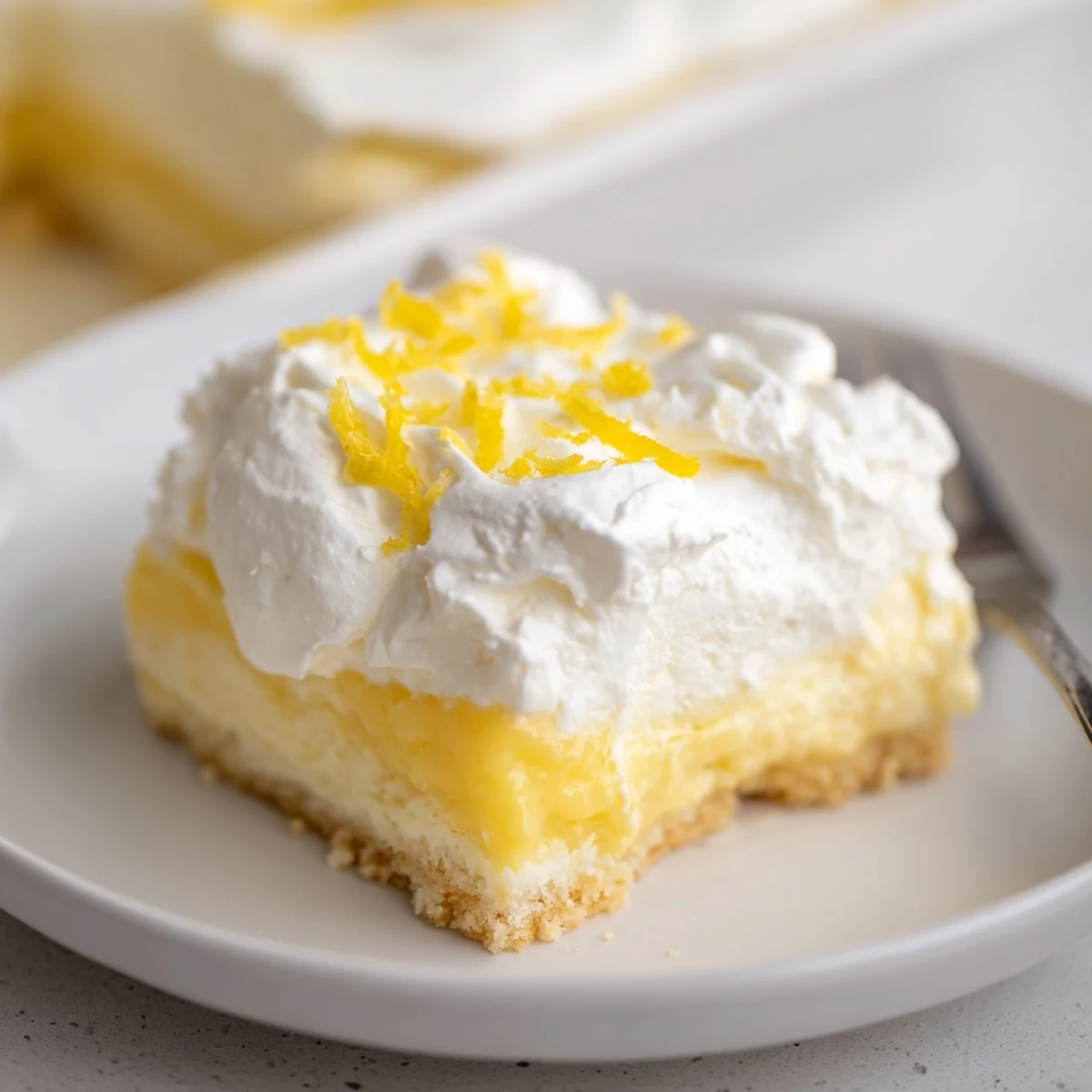Slice of Lemon Lush Cake showing fluffy whipped topping and tangy pudding.