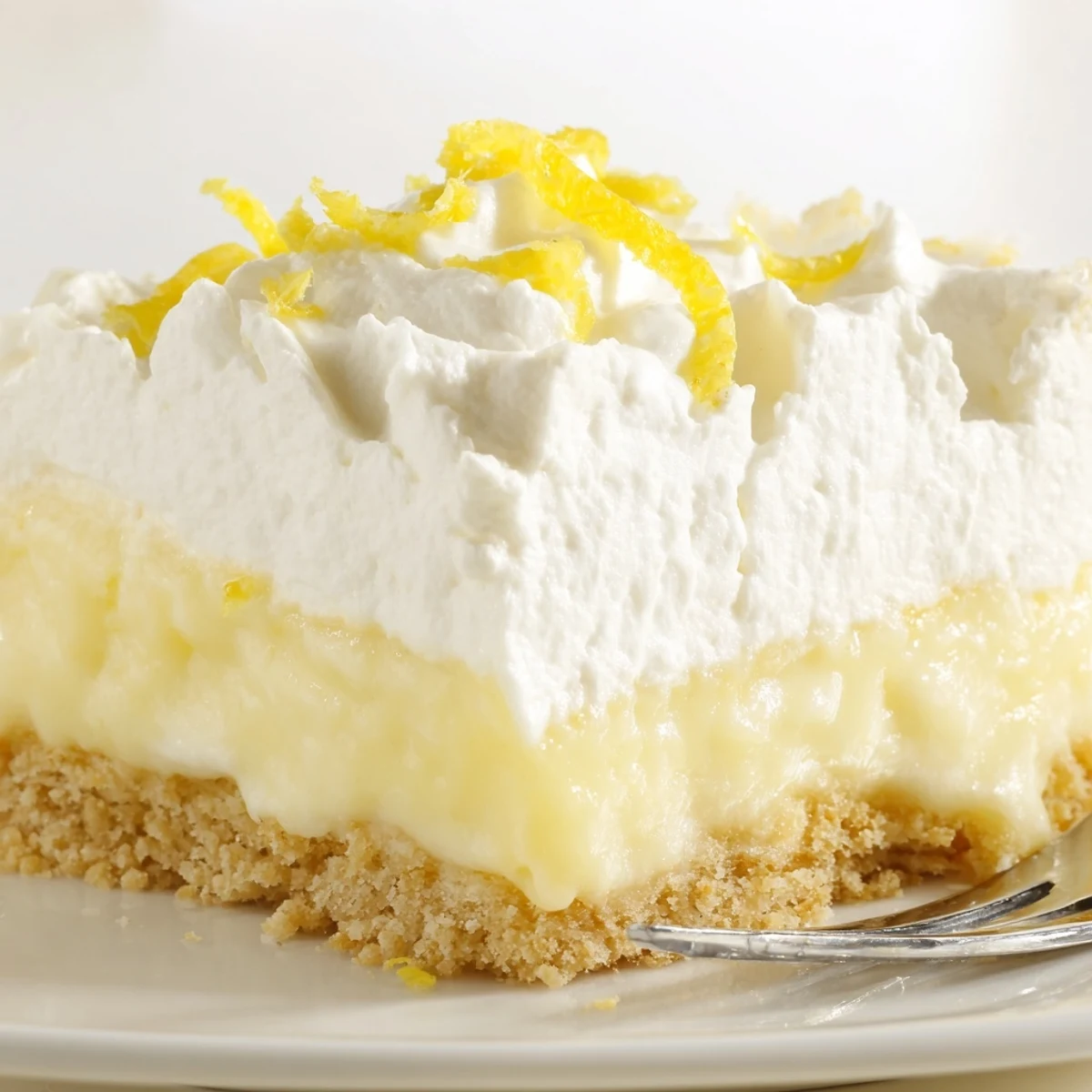 Lemon Lush Cake with creamy layers on chilled dish, bright lemon zest.