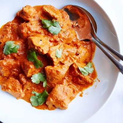 Tender Crockpot Butter Chicken served over fluffy basmati rice in a creamy orange sauce